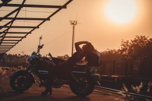 A woman enjoys the golden hour as she poses on a motorcycle, creating a stunning silhouette against the sunset.
