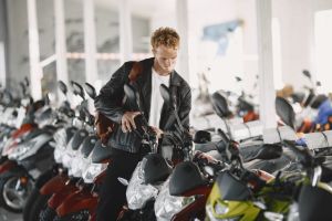 A young man examines a row of motorcycles inside a motor dealership, showcasing interest and choice.