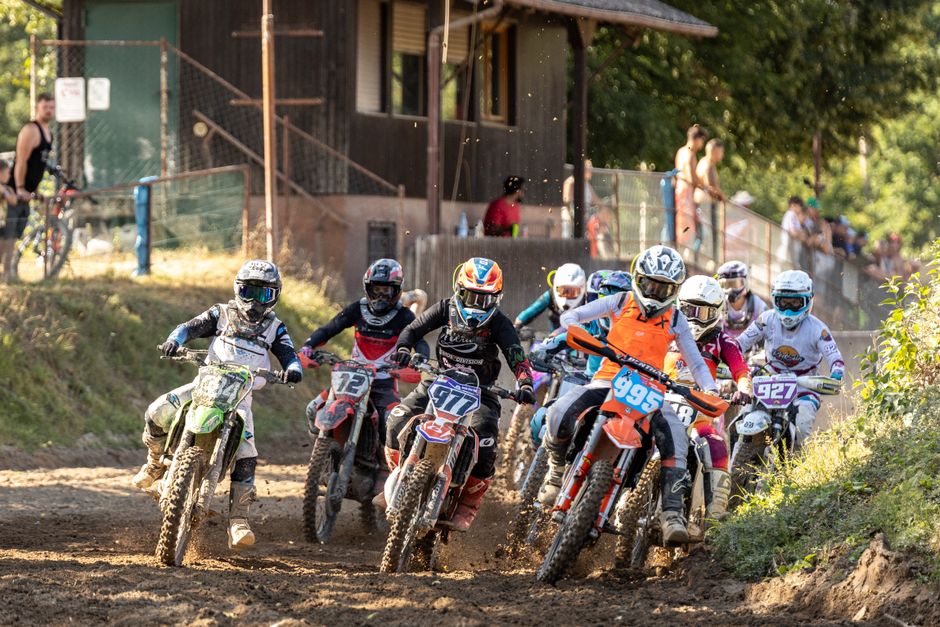 Dynamic motocross race with riders competing fiercely on a dirt track.